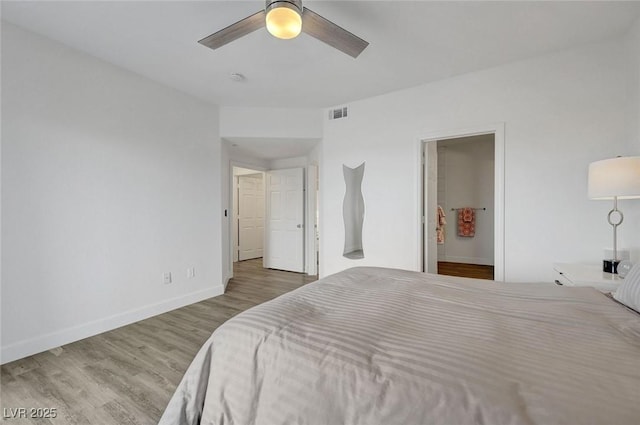 bedroom with baseboards, ensuite bath, visible vents, a ceiling fan, and wood finished floors