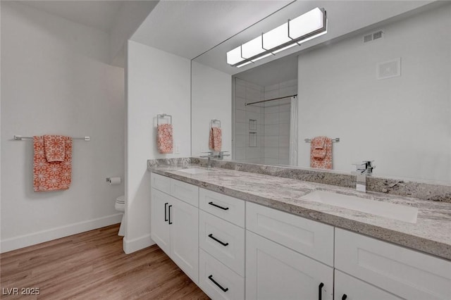 bathroom featuring a sink, visible vents, toilet, and wood finished floors