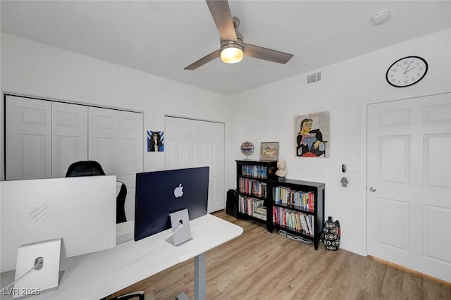 office area featuring visible vents, light wood-style floors, and a ceiling fan
