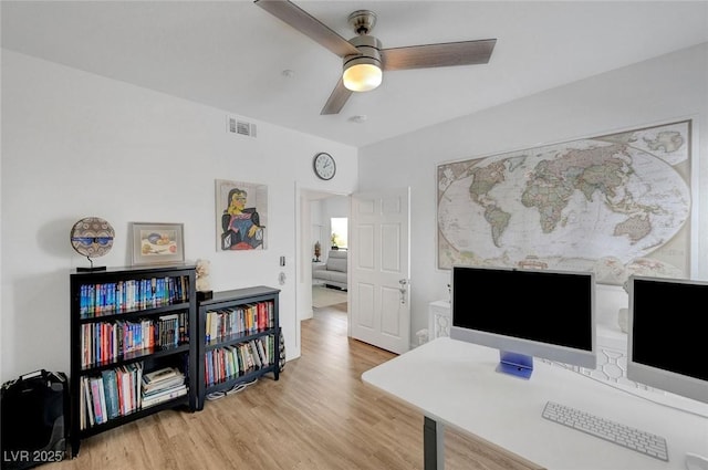 home office with a ceiling fan, visible vents, and wood finished floors