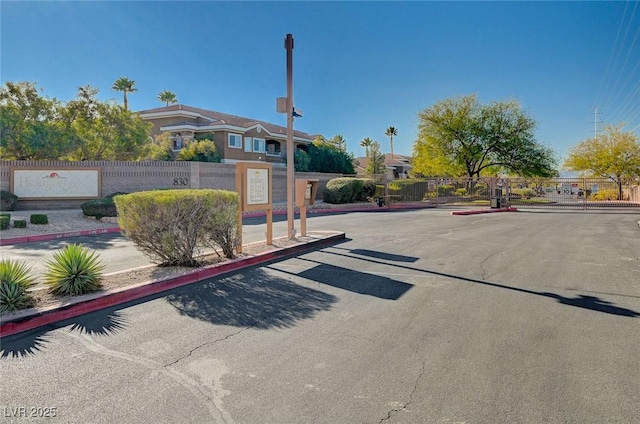 view of road featuring a gated entry, a gate, and curbs