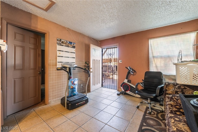 exercise room with light tile patterned floors and a textured ceiling