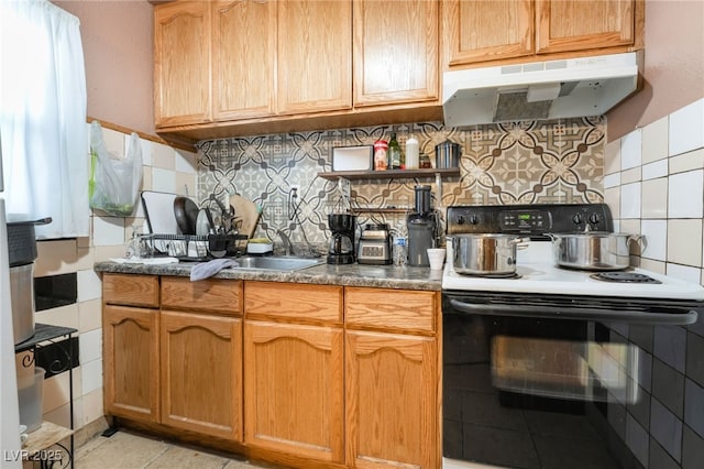 kitchen featuring tasteful backsplash, light tile patterned floors, dark countertops, under cabinet range hood, and electric range oven