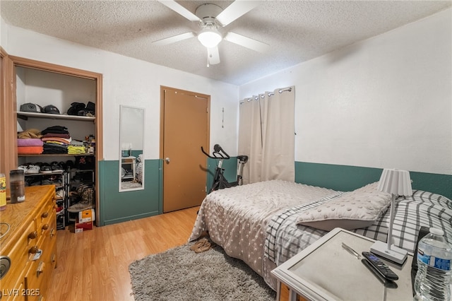 bedroom featuring a closet, a ceiling fan, wood finished floors, and a textured ceiling
