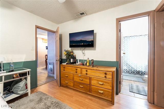 bedroom featuring a textured ceiling, light wood finished floors, and visible vents