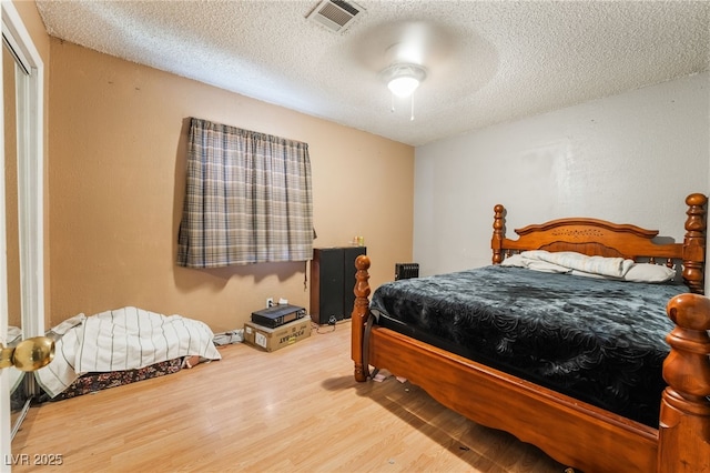 bedroom featuring visible vents, a closet, ceiling fan, a textured ceiling, and wood finished floors