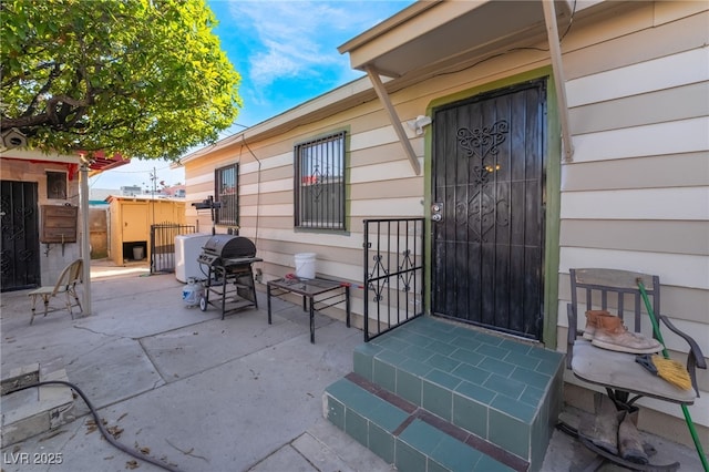 view of exterior entry featuring a patio area and fence