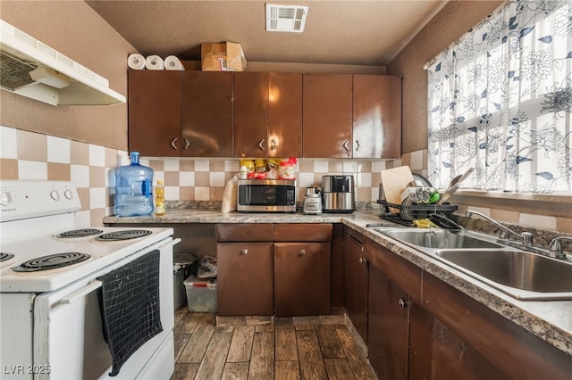 kitchen with a sink, electric stove, wood tiled floor, under cabinet range hood, and stainless steel microwave