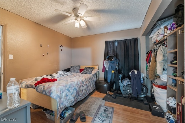 bedroom featuring a textured ceiling, a ceiling fan, and wood finished floors