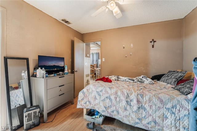 bedroom with visible vents, ceiling fan, a textured ceiling, and light wood-style flooring