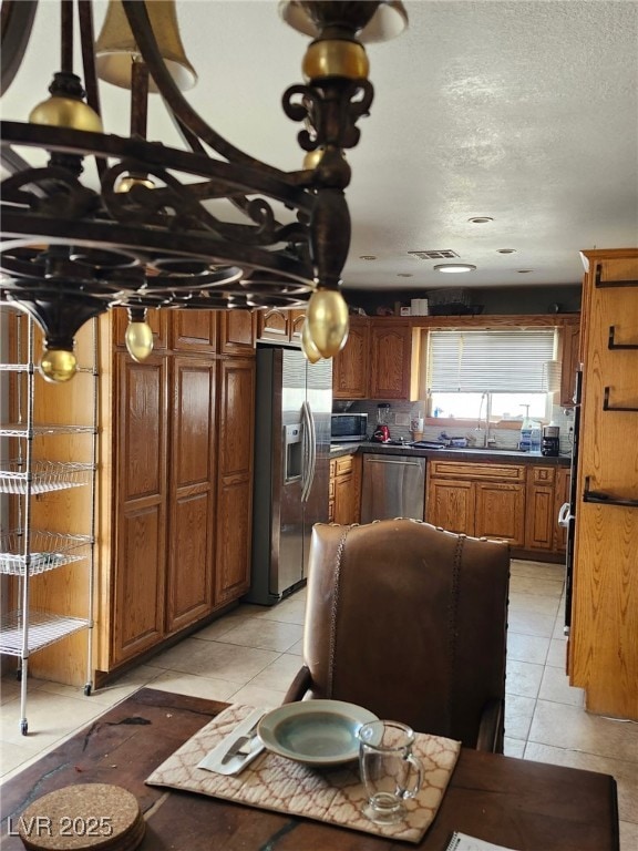1812 Ivanhoe Way, Las Vegas, NV 89102 - kitchen with appliances with stainless steel finishes, brown cabinetry, a sink, light tile patterned floors, and a textured ceiling