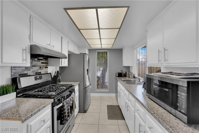 1440 Vegas Valley Dr Unit 1, Las Vegas, NV 89169 - kitchen featuring under cabinet range hood, appliances with stainless steel finishes, a sink, light tile patterned floors, and decorative backsplash