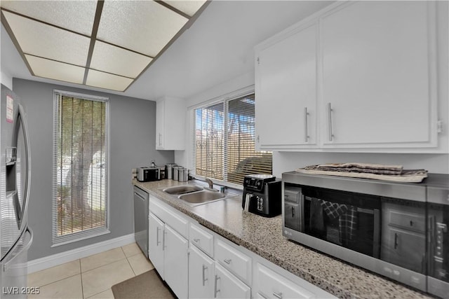 1440 Vegas Valley Dr Unit 1, Las Vegas, NV 89169 - kitchen with stainless steel appliances, baseboards, a sink, light tile patterned floors, and white cabinets