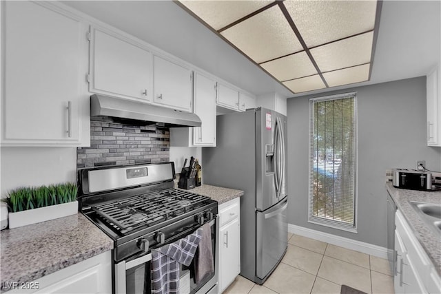 1440 Vegas Valley Dr Unit 1, Las Vegas, NV 89169 - kitchen with under cabinet range hood, stainless steel appliances, light tile patterned flooring, and white cabinetry