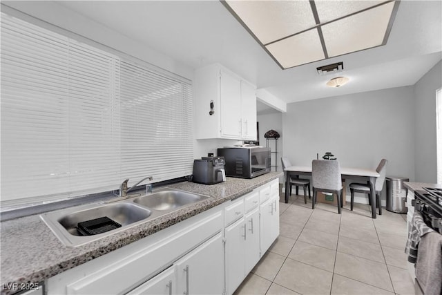 1440 Vegas Valley Dr Unit 1, Las Vegas, NV 89169 - kitchen with stainless steel microwave, a sink, light tile patterned floors, white cabinetry, and light countertops