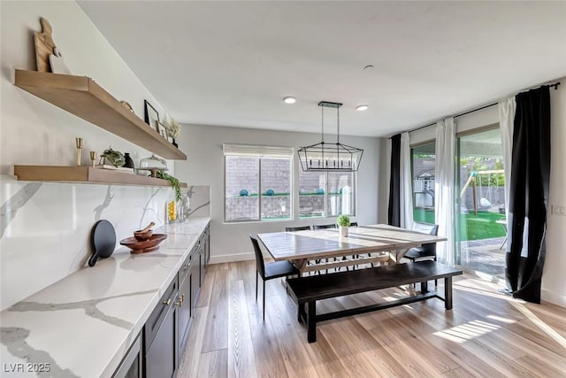 dining room with plenty of natural light, light wood finished floors, baseboards, and a notable chandelier