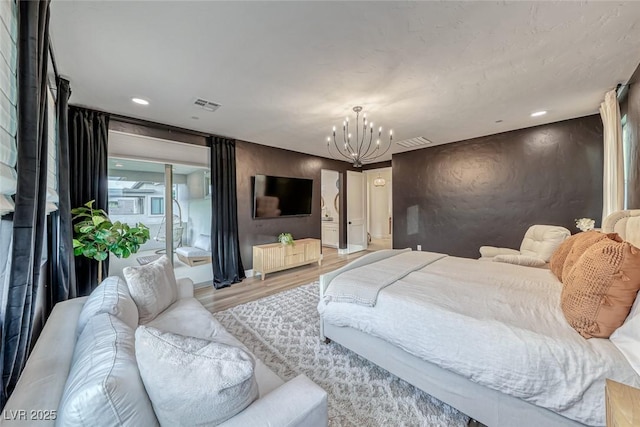 bedroom featuring wood finished floors, visible vents, baseboards, and a notable chandelier