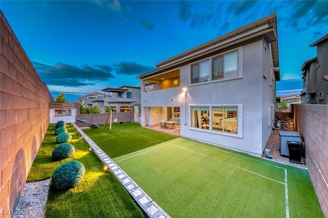 back of property with a fenced backyard, a balcony, a yard, stucco siding, and a patio area
