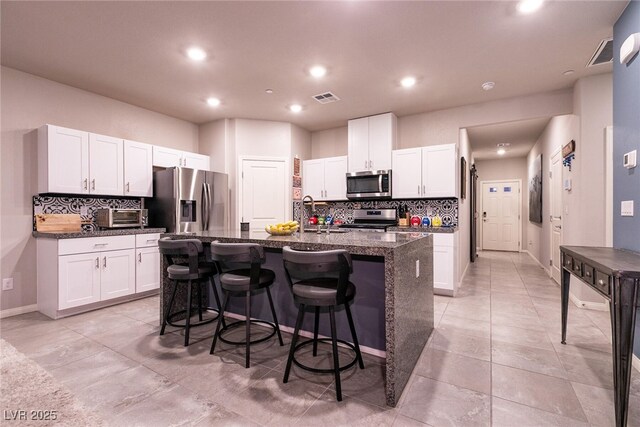 10125 Sequoia Falls Pl, Las Vegas, NV 89149 - kitchen with stainless steel appliances, decorative backsplash, a sink, an island with sink, and a breakfast bar area