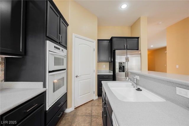 9173 Whitekirk Pl, Las Vegas, NV 89145 - kitchen with stainless steel fridge with ice dispenser, a sink, dark cabinets, double oven, and recessed lighting