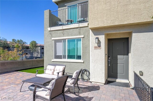 6804 Surf Green Ct, North Las Vegas, NV 89086 - entrance to property featuring a balcony, stucco siding, fence, and a patio