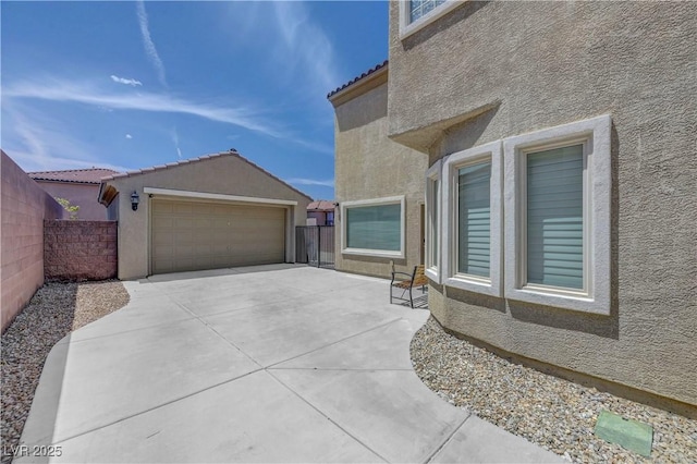 view of side of property with stucco siding, a tile roof, and fence