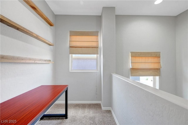 hallway with carpet flooring, baseboards, and an upstairs landing