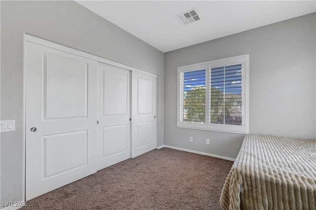 unfurnished bedroom featuring carpet floors, baseboards, a closet, and visible vents