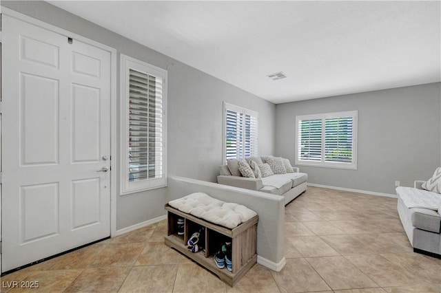 living room with light tile patterned floors, baseboards, and visible vents