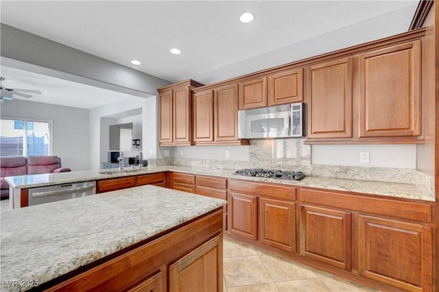kitchen featuring brown cabinetry, stainless steel appliances, open floor plan, recessed lighting, and light tile patterned floors
