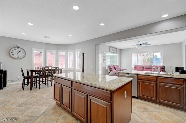 kitchen featuring stainless steel dishwasher, light tile patterned floors, a kitchen island, and a sink