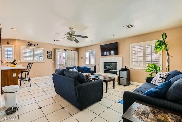 living area with baseboards, visible vents, a healthy amount of sunlight, and a ceiling fan