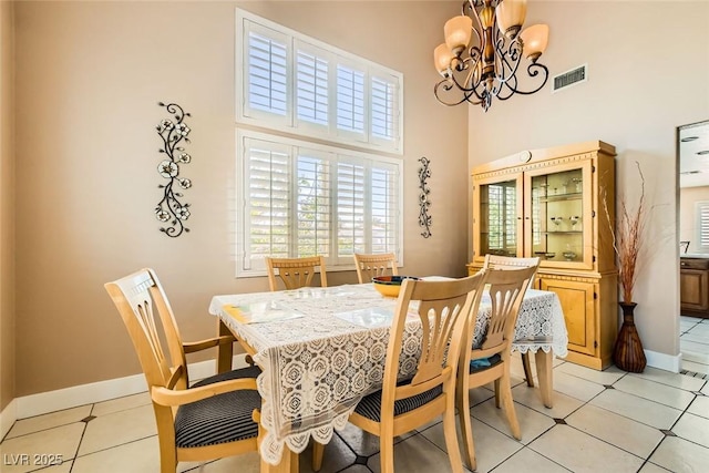 dining room with baseboards, a towering ceiling, visible vents, and an inviting chandelier