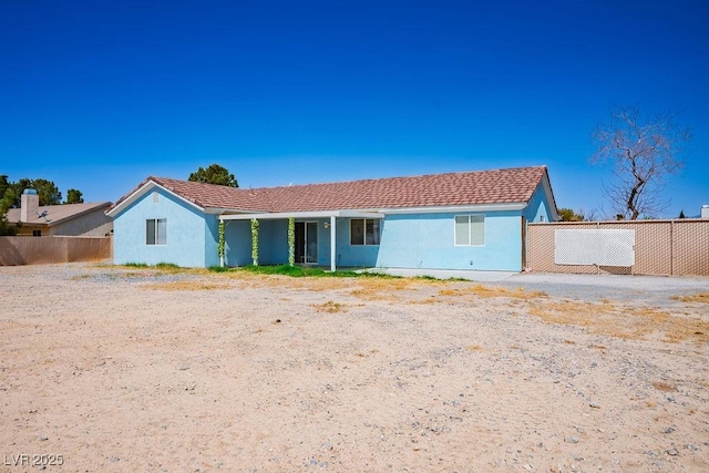 ranch-style house featuring stucco siding and fence