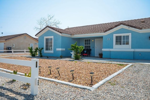 view of front of house featuring a tiled roof, stucco siding, and fence