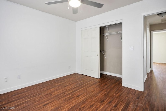 unfurnished bedroom featuring dark wood-style flooring, a closet, baseboards, and ceiling fan