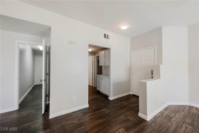 spare room with dark wood-type flooring, baseboards, and visible vents