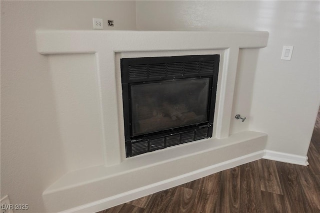 interior details with baseboards, wood finished floors, and a glass covered fireplace