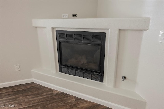 room details with a glass covered fireplace, baseboards, and wood finished floors