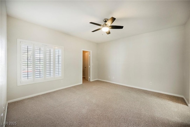 carpeted spare room featuring baseboards and ceiling fan