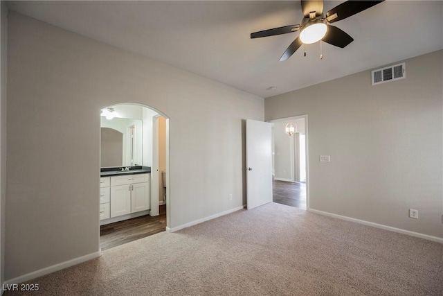 unfurnished bedroom with baseboards, carpet floors, arched walkways, connected bathroom, and visible vents