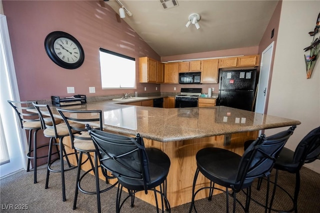 kitchen with vaulted ceiling, a sink, visible vents, a peninsula, and black appliances