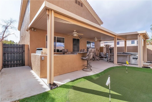 6790 Gold Yarrow St, Las Vegas, NV 89148 - fenced backyard featuring a hot tub, a patio, a putting green, ceiling fan, and an outdoor bar