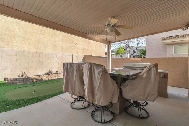 6790 Gold Yarrow St, Las Vegas, NV 89148 - fenced backyard with a putting area, a patio area, exterior kitchen, and ceiling fan