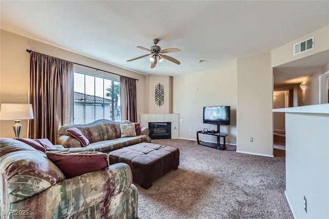 carpeted living area featuring baseboards, visible vents, ceiling fan, and a fireplace