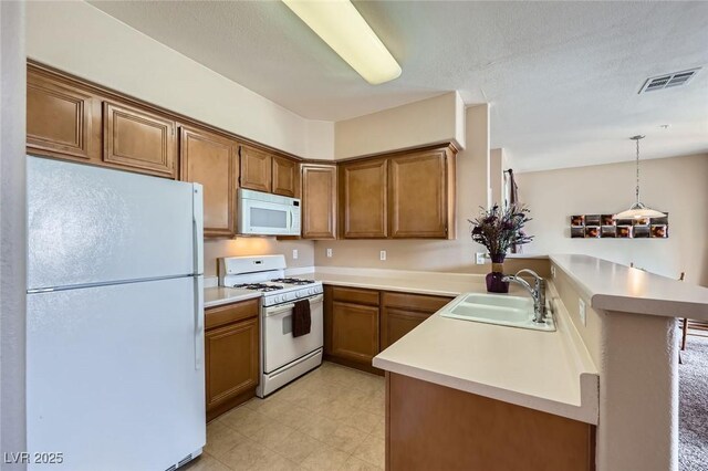 kitchen with visible vents, white appliances, brown cabinetry, and a sink