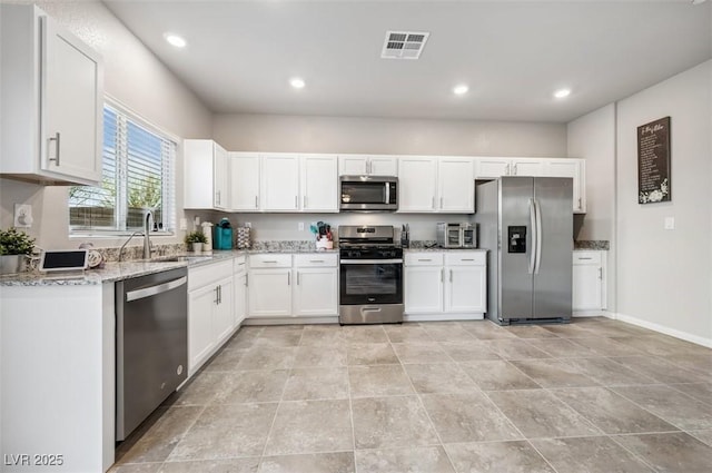 9068 Lennon Ln, Las Vegas, NV 89113 - kitchen with a sink, visible vents, white cabinets, light stone countertops, and appliances with stainless steel finishes