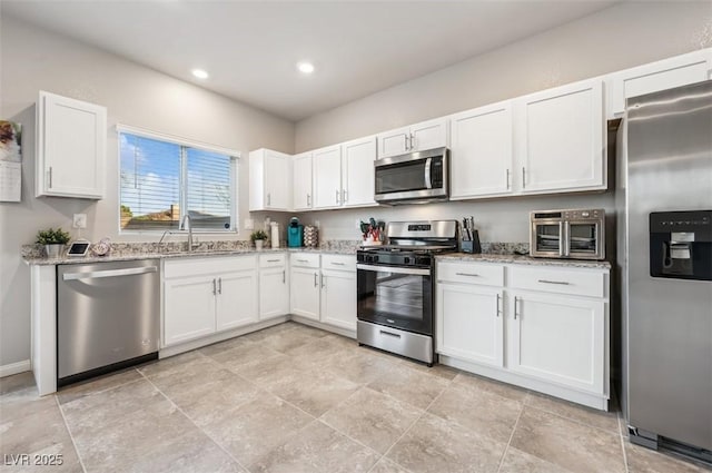 9068 Lennon Ln, Las Vegas, NV 89113 - kitchen with a sink, stainless steel appliances, a toaster, white cabinetry, and light stone countertops