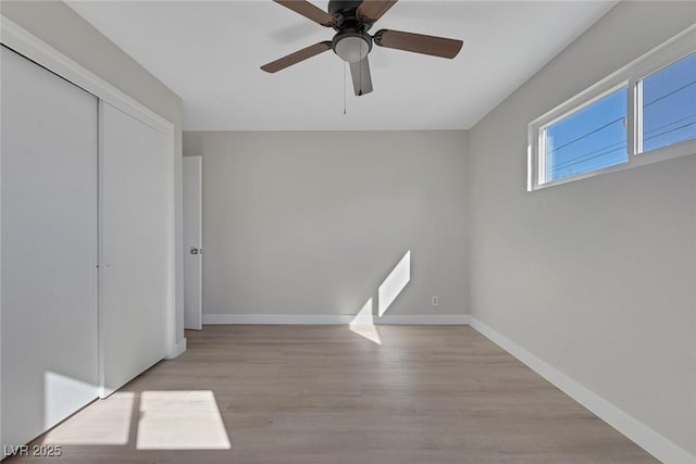 unfurnished bedroom with baseboards, a closet, wood finished floors, and ceiling fan
