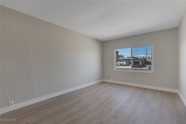 unfurnished room featuring baseboards and wood finished floors